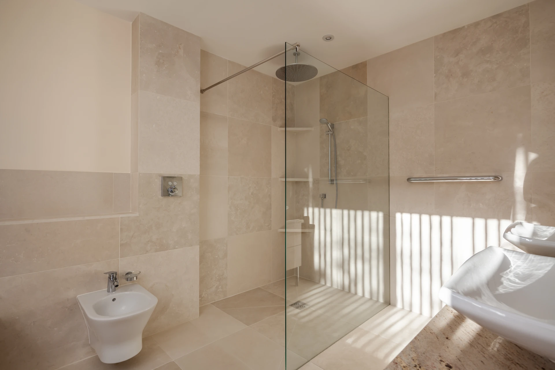 Salle de bain moderne avec douche à l'italienne vitrée, carrelage beige grand format effet marbre