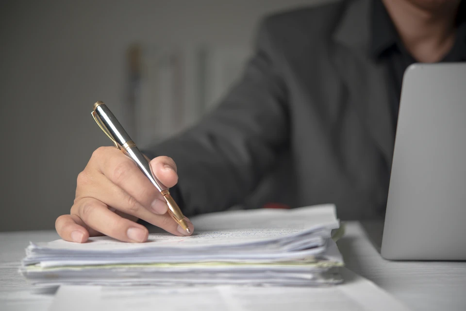 Réunion d'affaires dans un bureau moderne avec deux hommes en costumes analysant des documents contractuels