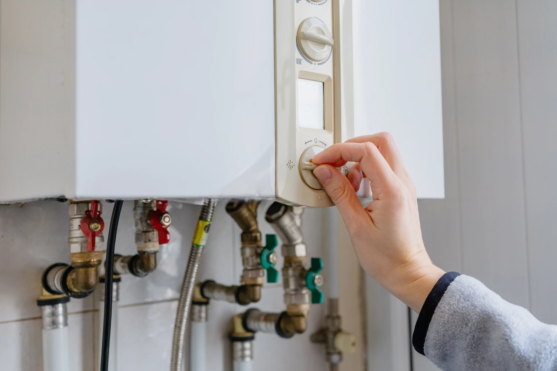 Deux mains d'âges différents - une main plus expérimentée d'un homme mûr et une main plus jeune d'un homme adulte - travaillant ensemble à l'installation ou à la maintenance d'un système de chauffage. Les deux hommes sont photographiés de profil ou en plan rapproché, concentrés sur leur tâche commune. L'arrière-plan montre un intérieur résidentiel ou un atelier professionnel bien équipé. La lumière naturelle ou l'éclairage de l'atelier doit créer une atmosphère chaleureuse et professionnelle. L'image doit transmettre la collaboration, le partage de savoir-faire et la confiance entre les générations.